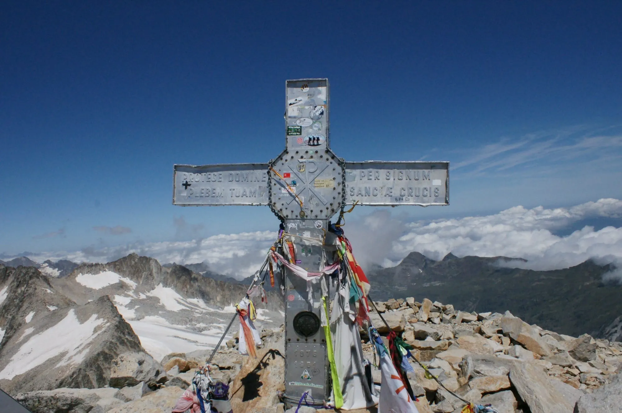 La cruz de la cima del Aneto vista de frente, con el Pirineo nevado al fondo