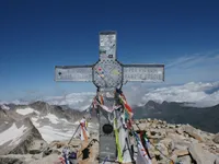 La cruz de la cima del Aneto vista de frente, con el Pirineo nevado al fondo