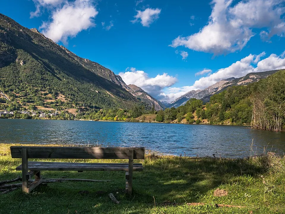 Un banco con vistas al embalse de Eriste o Linsoles, rodeado de bosque y montañas, en el Valle de Benasque