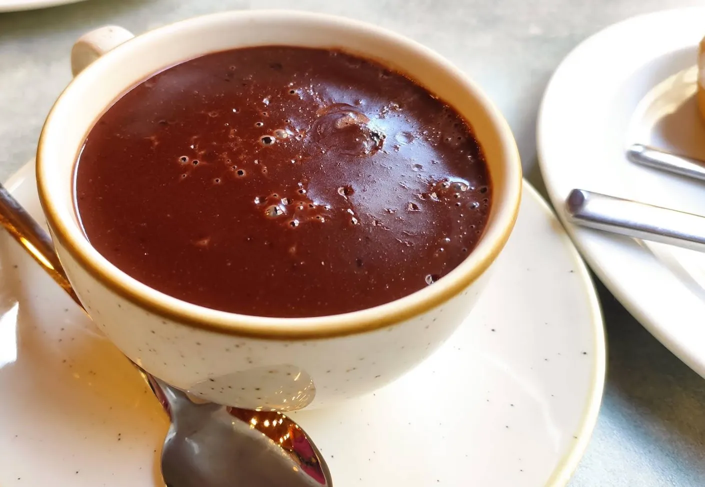 Taza de chocolate a la taza, espeso y brillante, servida en taza de cerámica con su platillo y cuchara