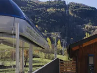 Cabina del telecabina Benasque-Cerler en la estación base, con la línea de torres subiendo por la ladera boscosa al fondo
