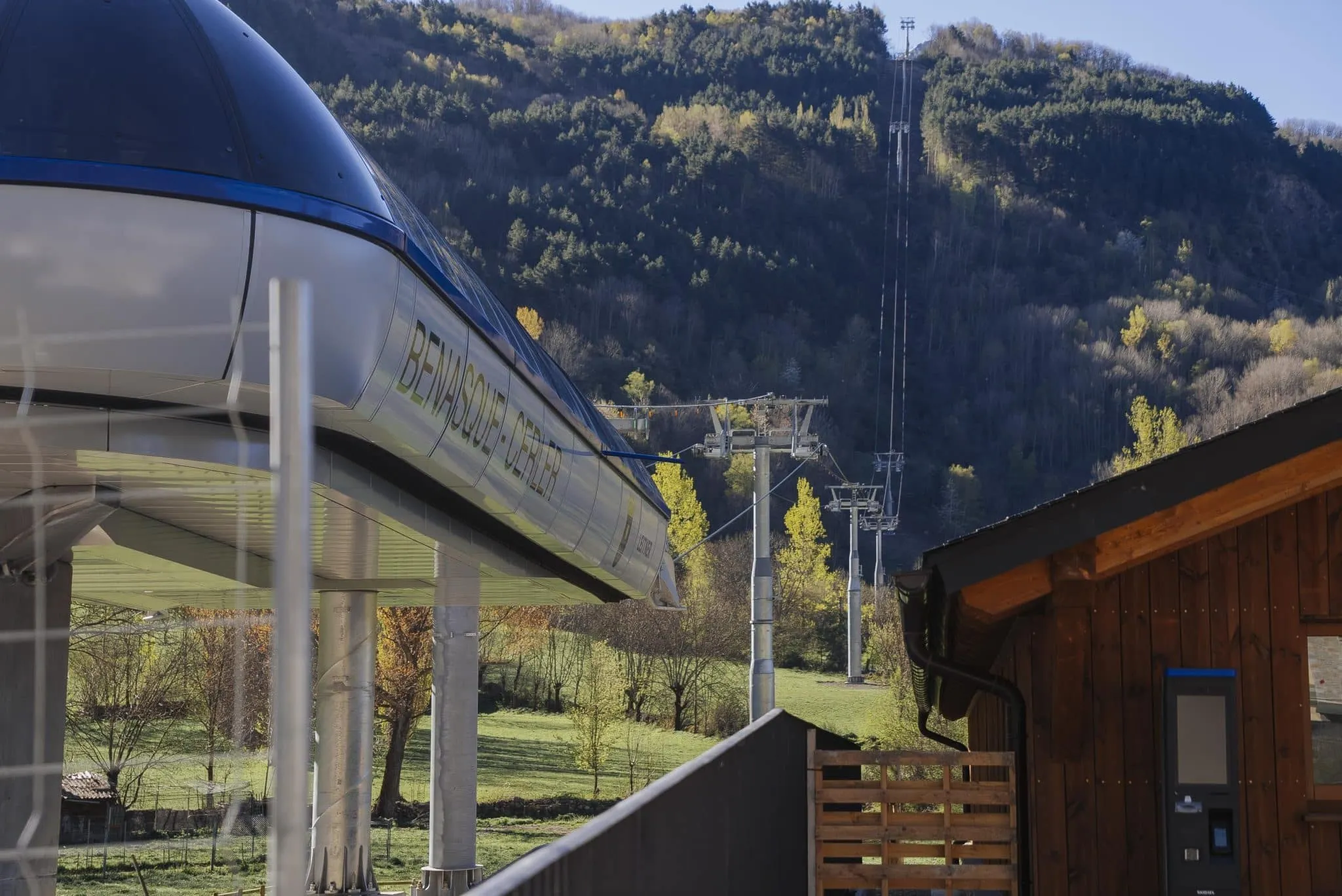 Cabina del telecabina Benasque-Cerler en la estación base, con la línea de torres subiendo por la ladera boscosa al fondo